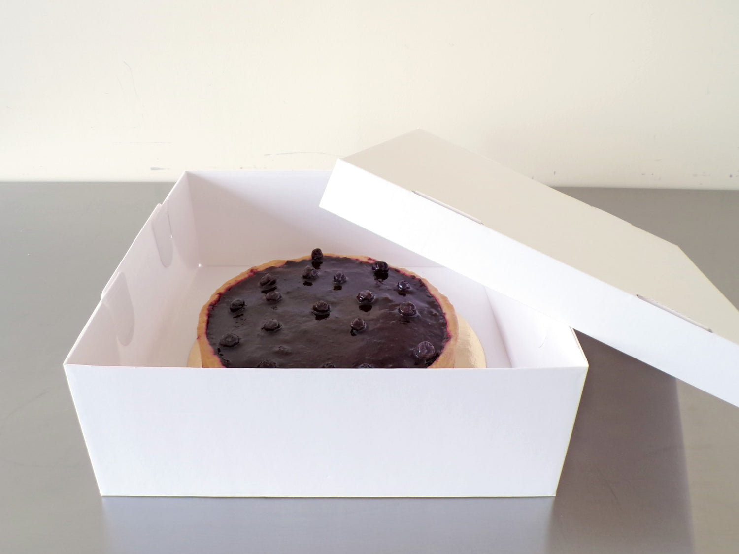 Geöffneter weißer Pappkarton mit Kuchen innen